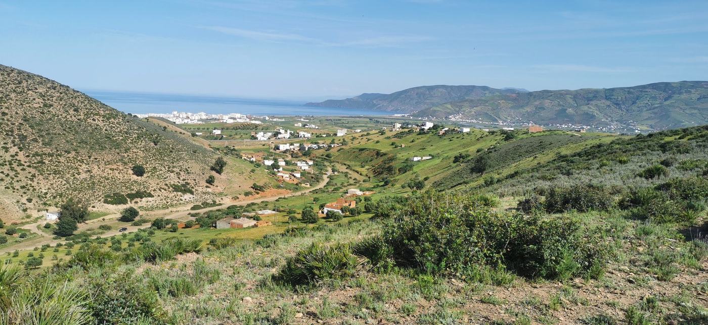 Wide view across the valley toward the Mediterranean coast, sea and coastal town in the distance